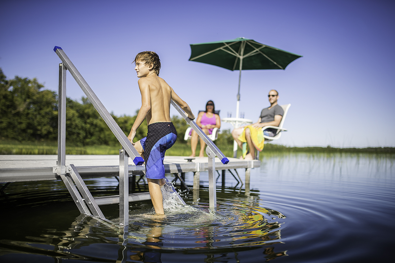 a young boy is standing on a dock in the water